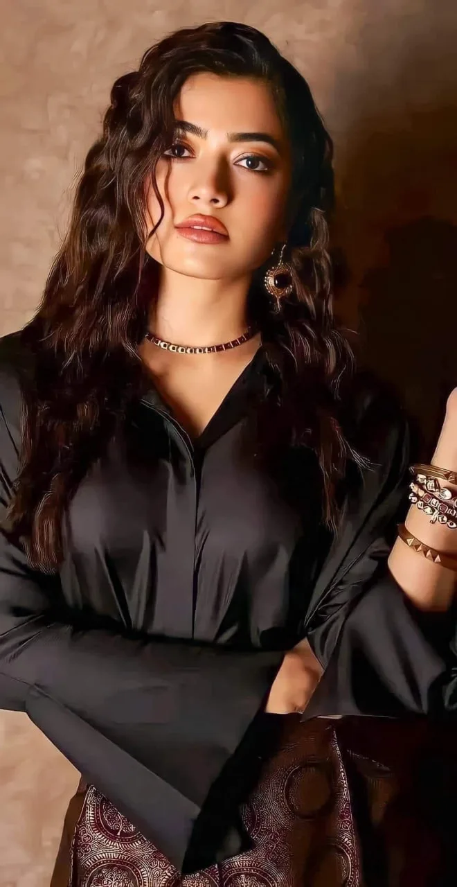 Rashmika Mandanna wearing a black satin shirt and chic jewelry
