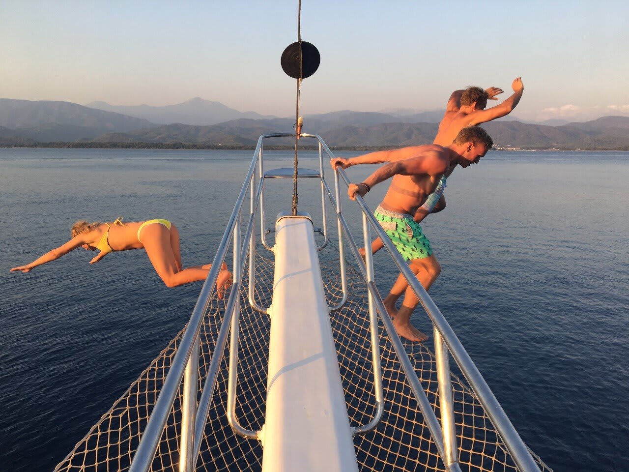 People Jumping Off A Yacht Into The Water Below