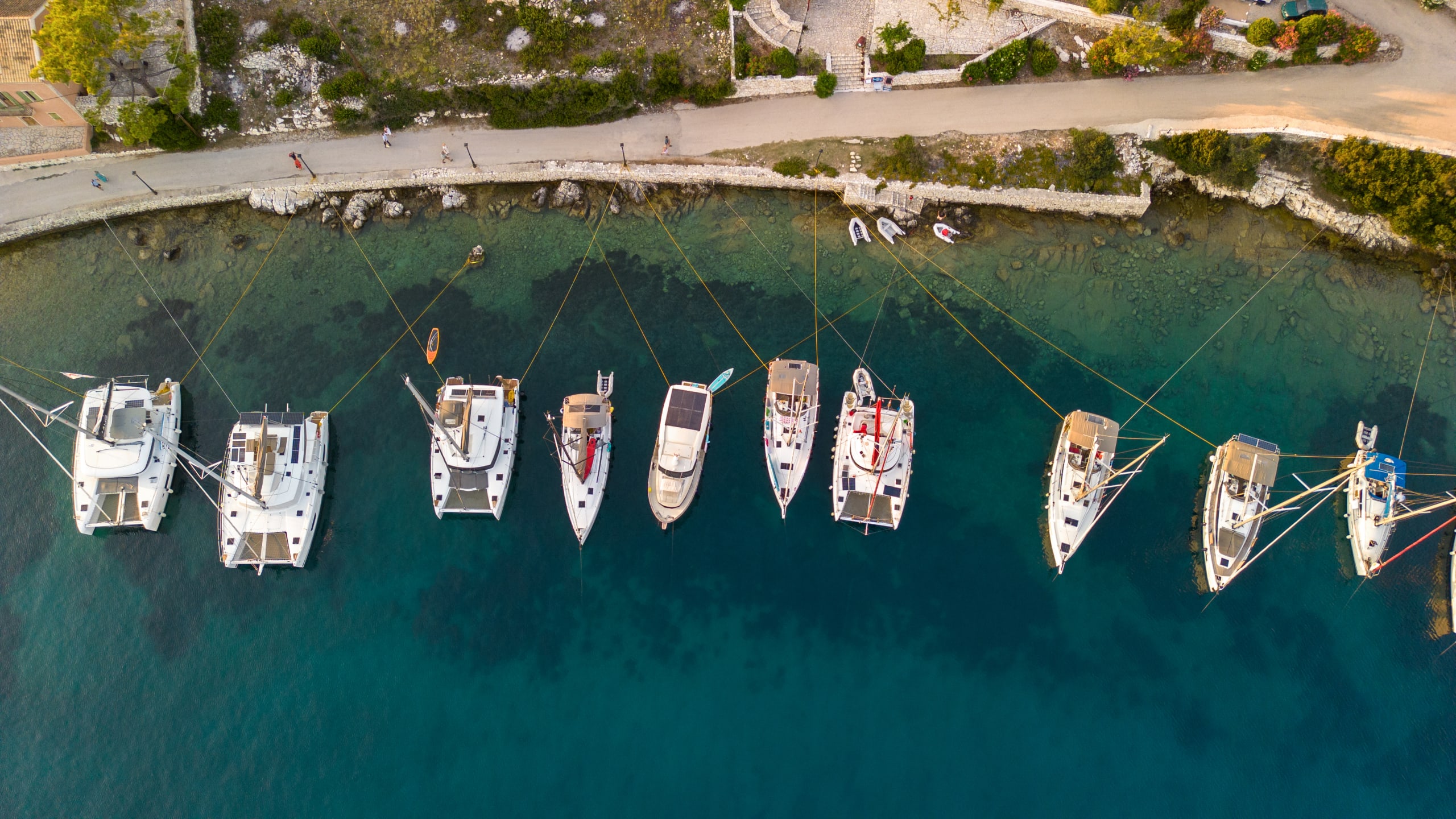 Sailboats and catamarans anchored in a beautiful bay of Fiscardo, Kefalonia, Greece. They are anchored in a row, view from above.