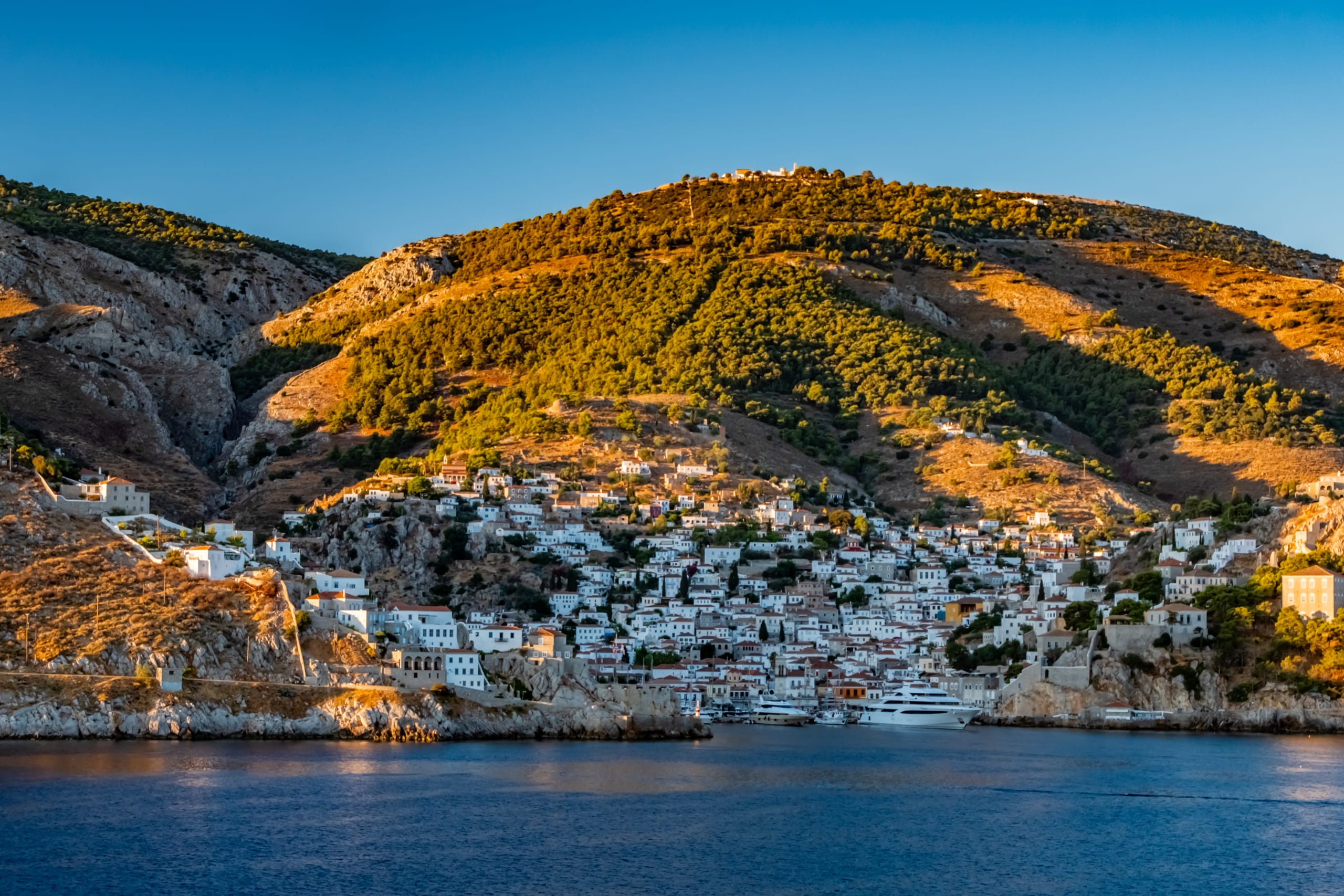 A view of the Greek island of Hydra. The view is from the sea as a cruise ship approaches the bay of Hydra in beautiful early morning light.