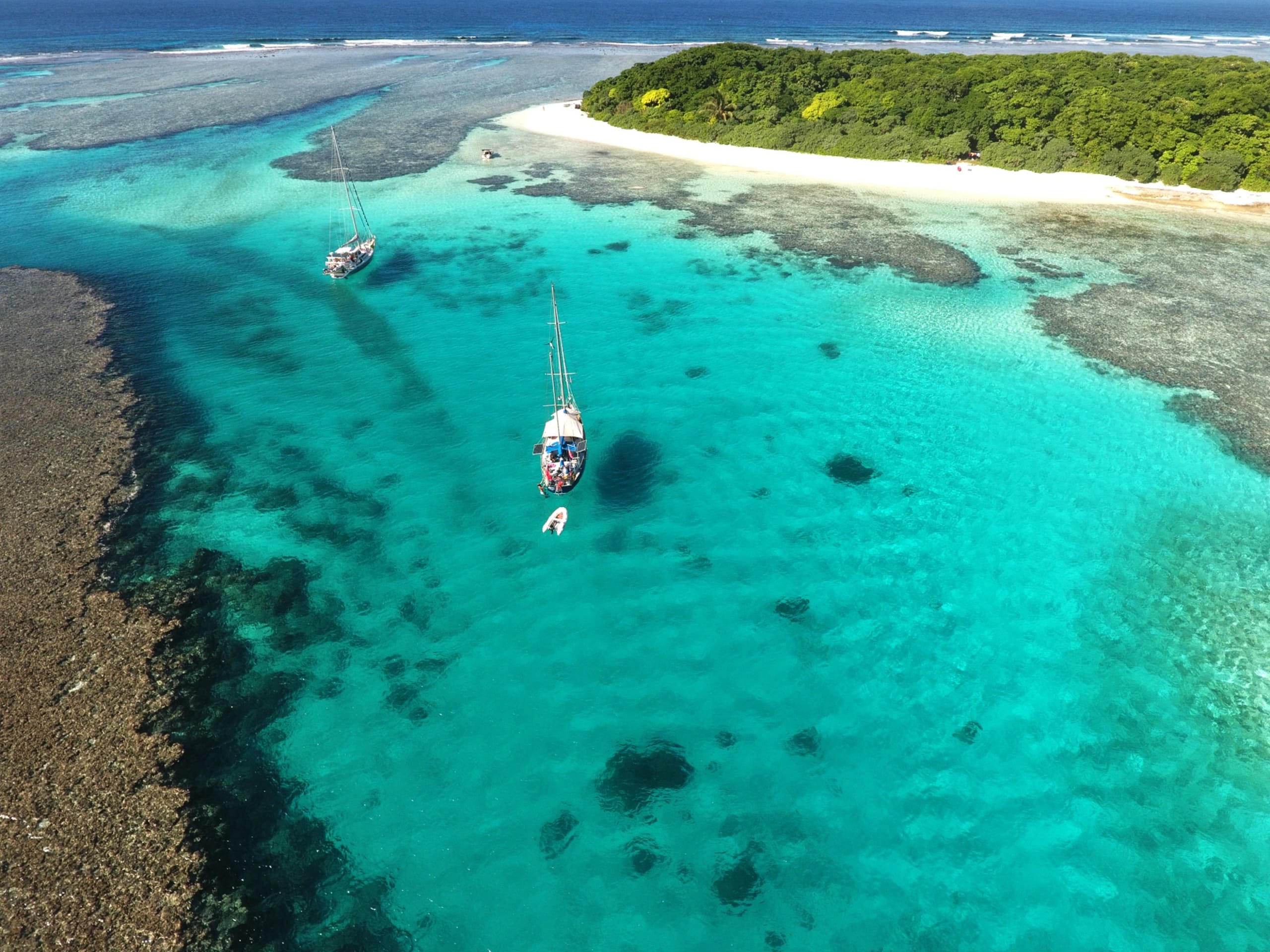Sailing boats anchored off of the Robinson Crusoe Island Manihiki in Tonga's Vav'u Island group