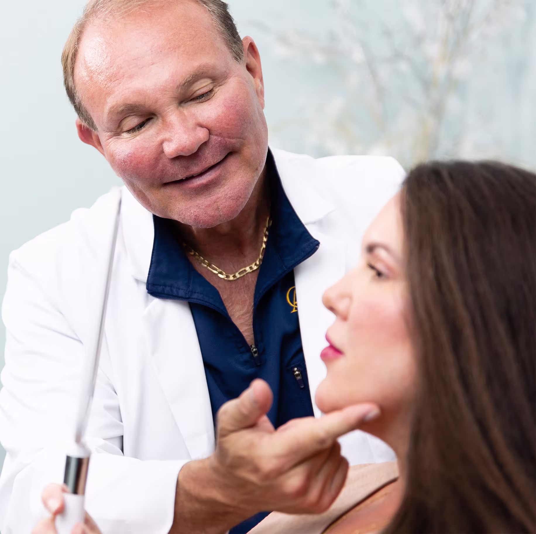 woman holding mirror to her face while doctor points to her chin