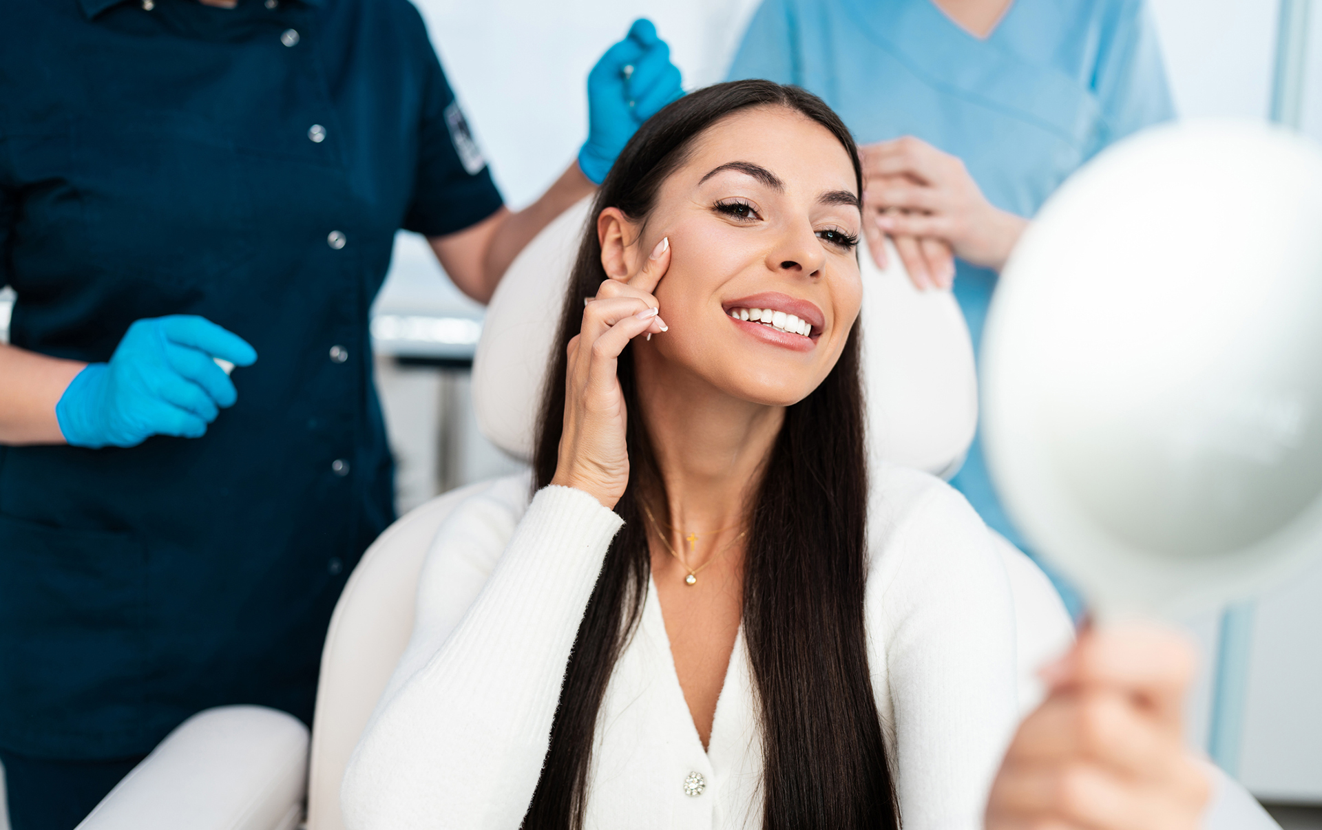 woman looking in hand mirror pointing to her face