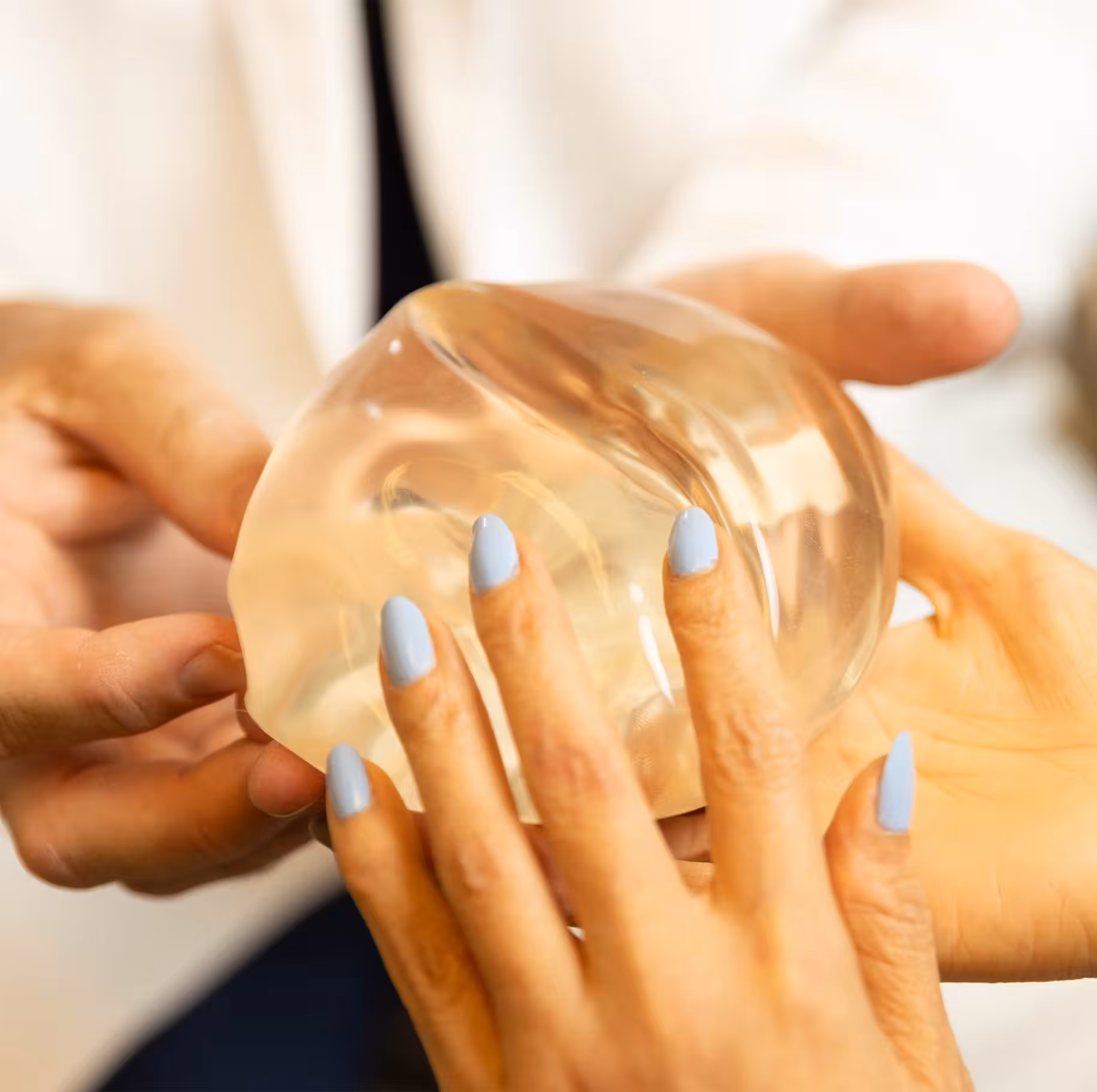 doctor and woman holding breast implant