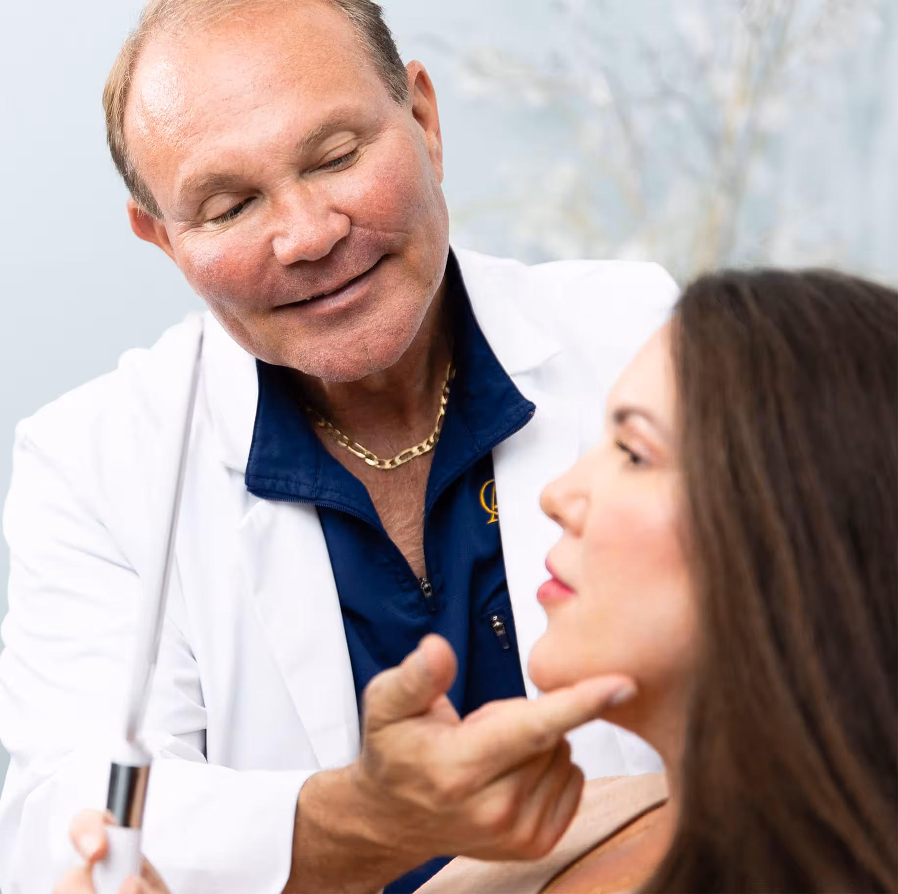 woman holding mirror to her face while doctor points to her chin