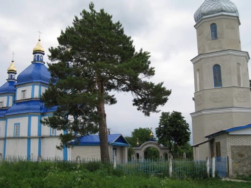 Дерев'яна церква Різдва Пресвятої Богородиці XVIII століття з синіми куполами та дзвіниця в селі Печера