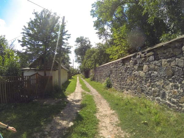 Грунтова дорога між кам'яною стіною та сільським будинком у Печері, Вінницька область