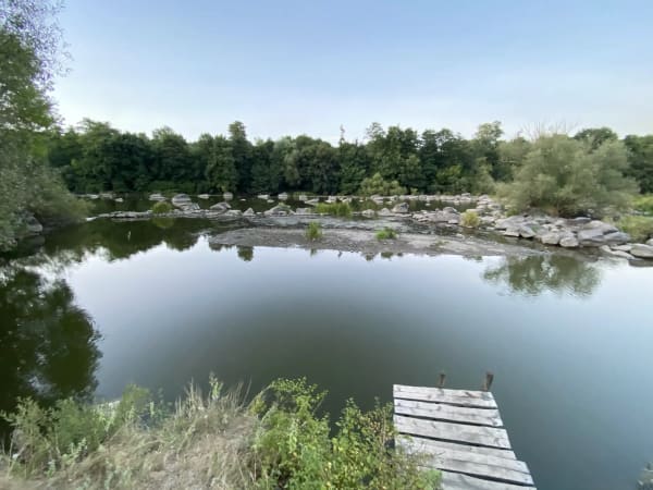 Мальовничі Печерські пороги на річці Південний Буг з дерев'яним пірсом та лісистими берегами