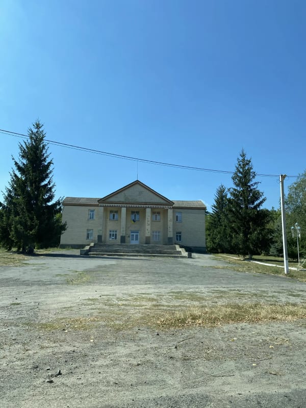Будинок культури в селі Печера, Вінницька область. Фасад будівлі з колонами, український прапор, ялинки.