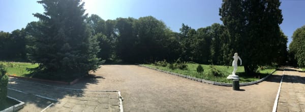 Панорамний вид на Печерський парк з алеями, зеленими насадженнями та білою скульптурою на передньому плані.