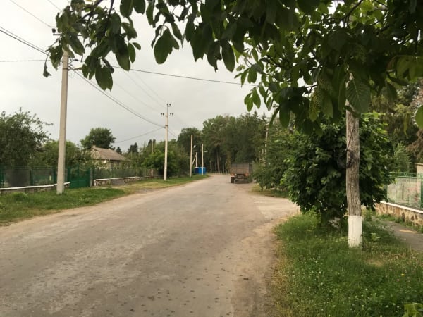 Сільська дорога в Печері, Вінницька область, з деревами, стовпами та вантажівкою на фоні