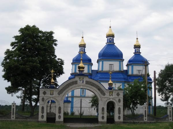 Церква Різдва Пресвятої Богородиці в селі Печера, Вінницька область, Україна. Дерев'яна церква з синіми куполами та золотими хрестами.