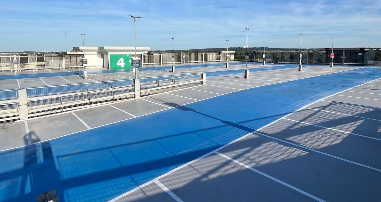 Rooftop car park deck coated in blue and grey with white bay lines.
