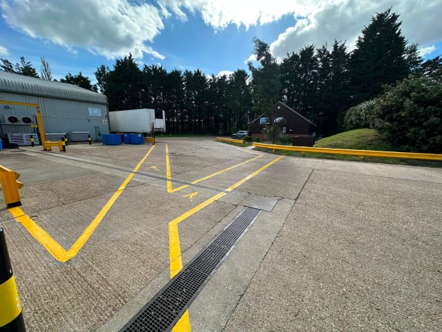 New yellow line marking on a concrete yard outside an industrial unit, Suffolk.