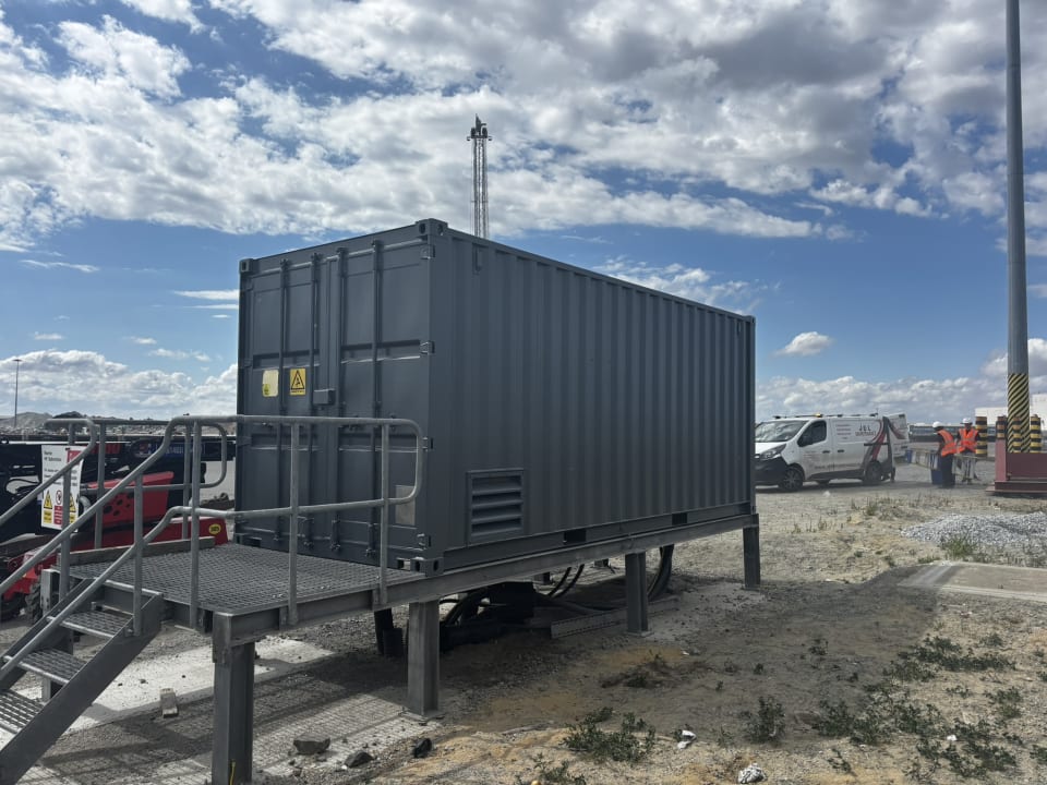Grey steel equipment container on a raised platform after coating, Great Yarmouth.