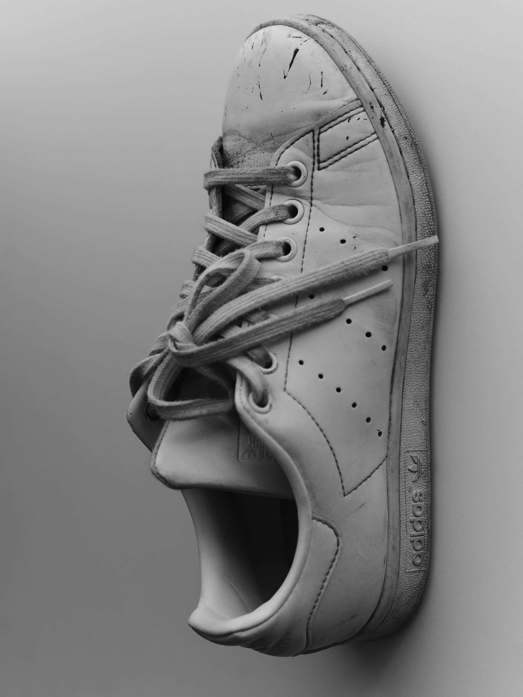 A single worn white adidas sneaker in profile.