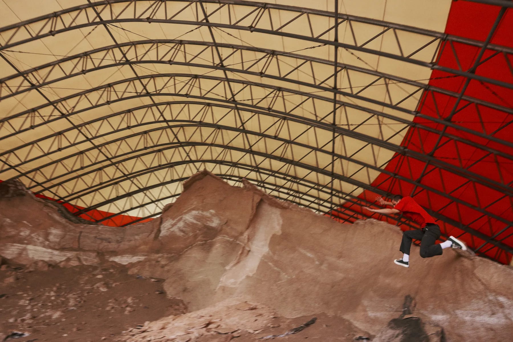 A red tarp draped over a ribbed canopy above a bank of pale rubble.