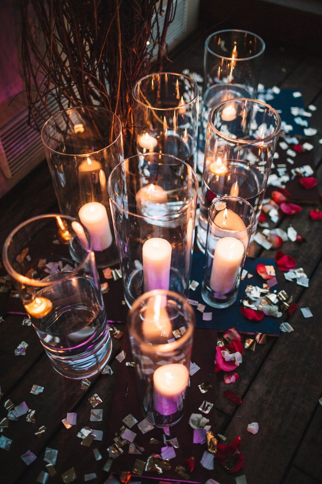 Various types of floating candle decorations arranged for an elegant wedding setting, featuring glass bowls, floral accents, and soft candlelight enhancing the romantic ambiance.

