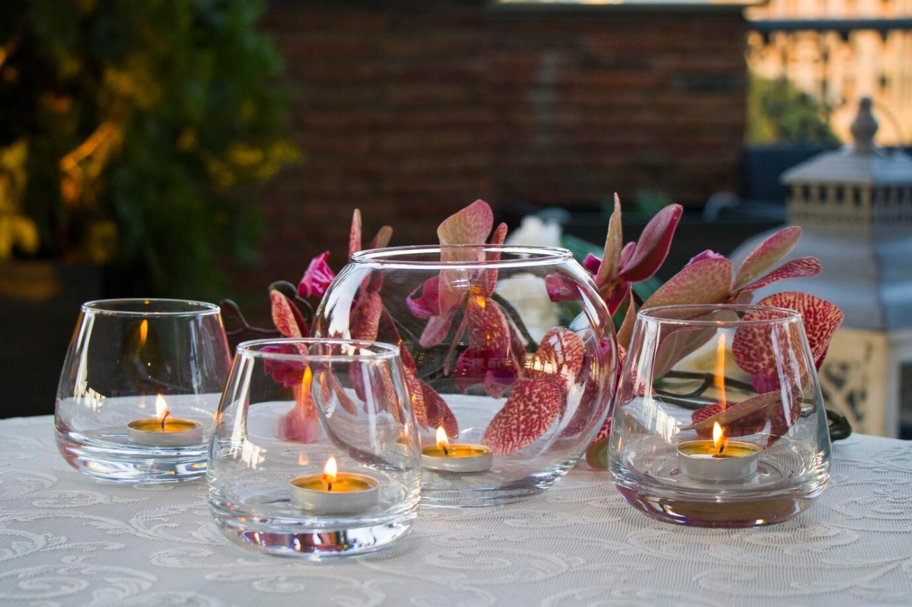 Elegant wedding table decorated with floating candles in glass bowls, surrounded by rose petals and soft lighting for a romantic ambiance.


