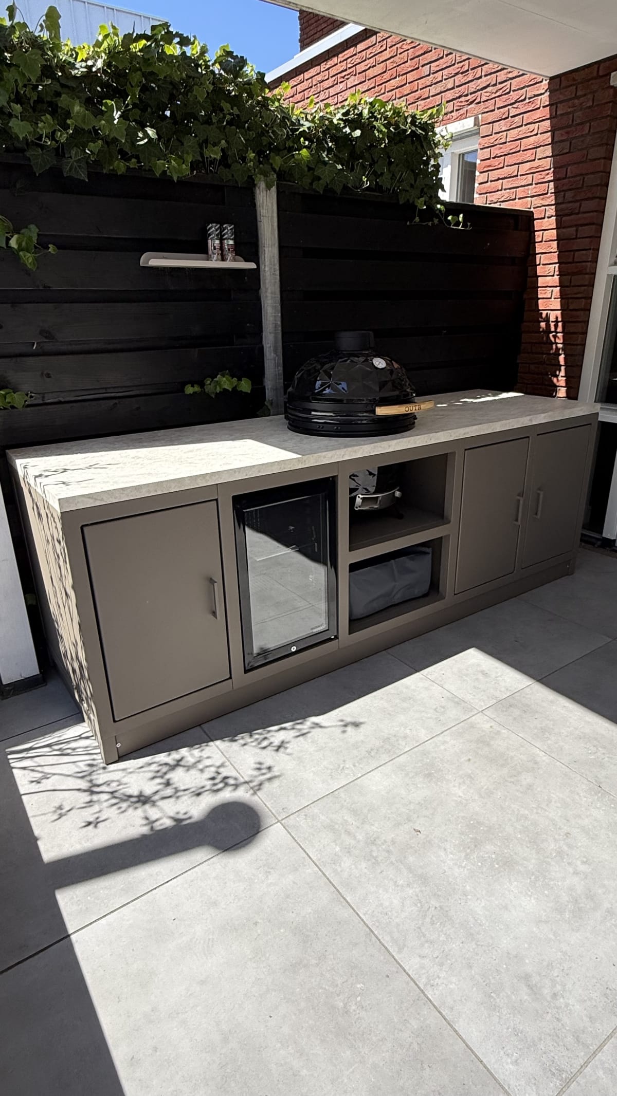 Taupe stalen buitenkeuken met koelkast en kamado in Borne