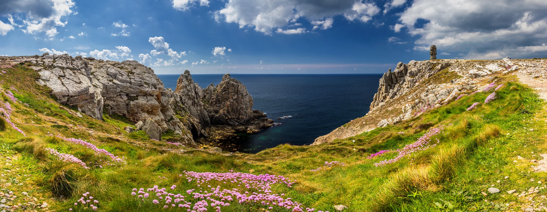 Panorama der Pointe de Pen-Hir in Camaret-sur-Mer, Bretagne, mit felsiger Küste und dem Aux Bretons Monument aus dem Zweiten Weltkrieg.