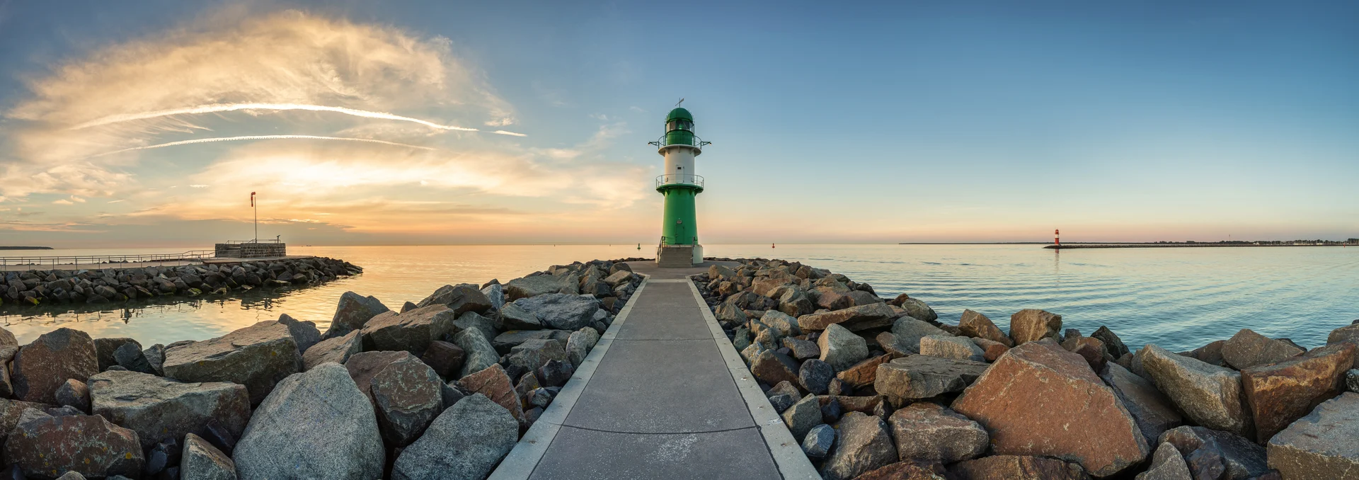 Leuchtturm auf einer Mole am Meer bei Sonnenuntergang.