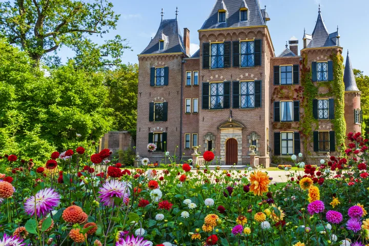 Schloss im Grünen mit buntem Blumenbeet im Vordergrund