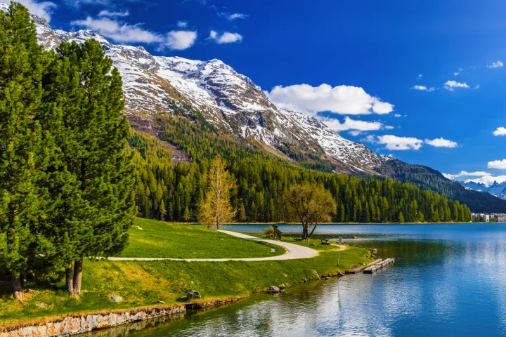 Berglandschaft mit See, blauem Himmel und strahlender Sonne.