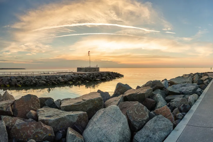Leuchtturm auf einer Mole am Meer bei Sonnenuntergang.