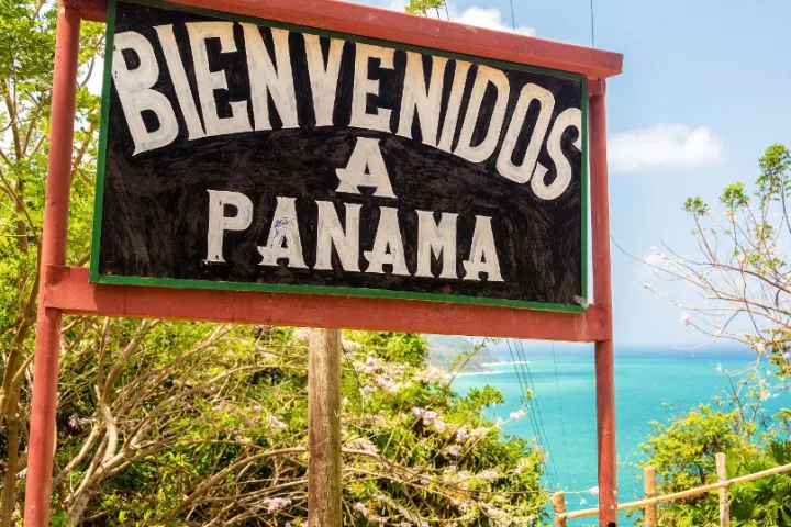 Willkommensschild in Panama vor tropischer Landschaft und Meer.