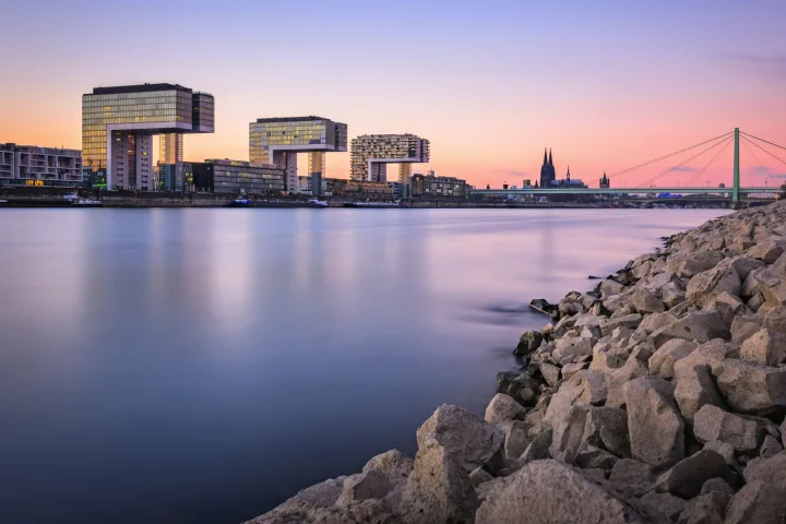 Stadtansicht von Köln mit Kranhäusern und Dom am Rheinufer bei Sonnenuntergang