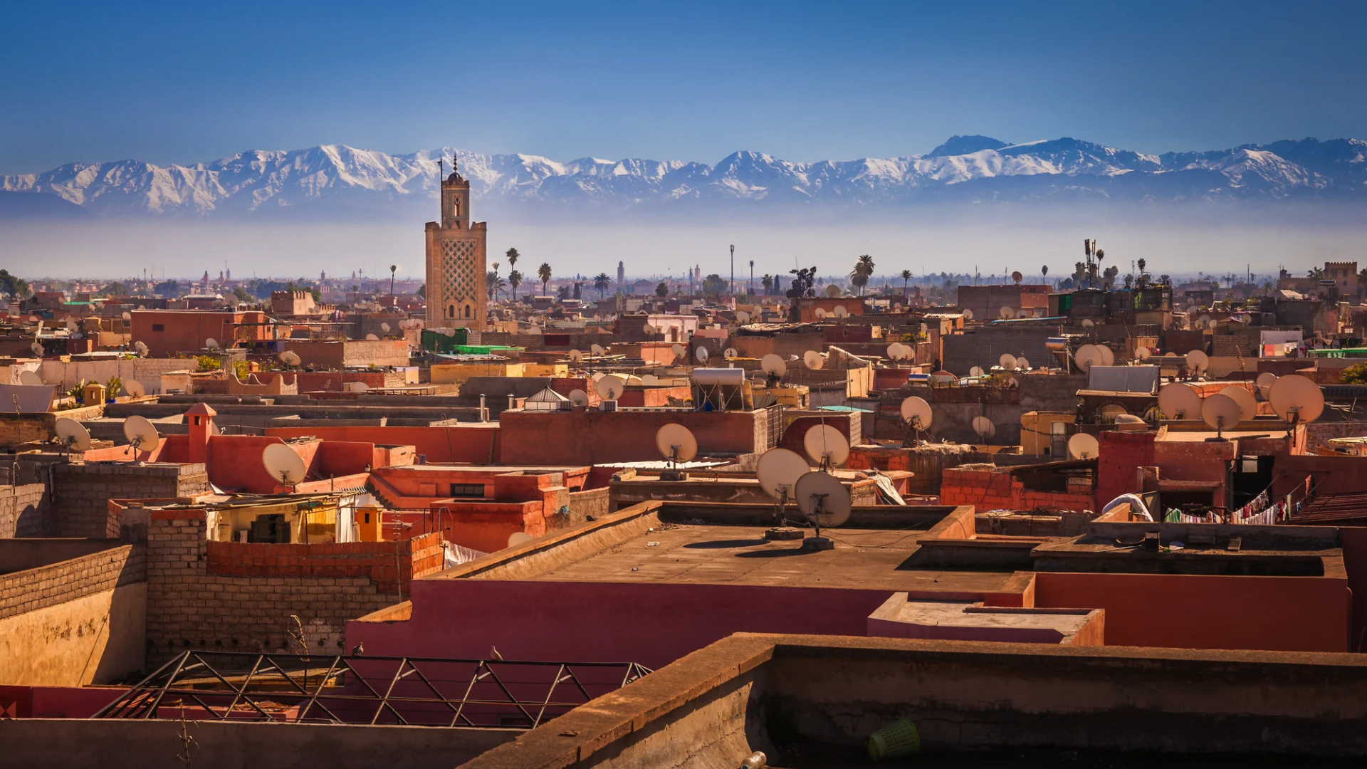 Panorama von Marrakesch mit Blick über die Dächer der Stadt, im Hintergrund das Atlasgebirge.