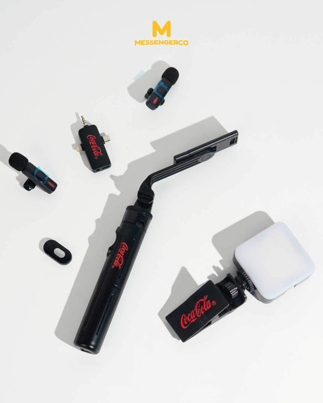 Branded media kit featuring a tripod, portable microphone, lamp, all positioned with a Coca-Cola logo for marketing and product showcase.