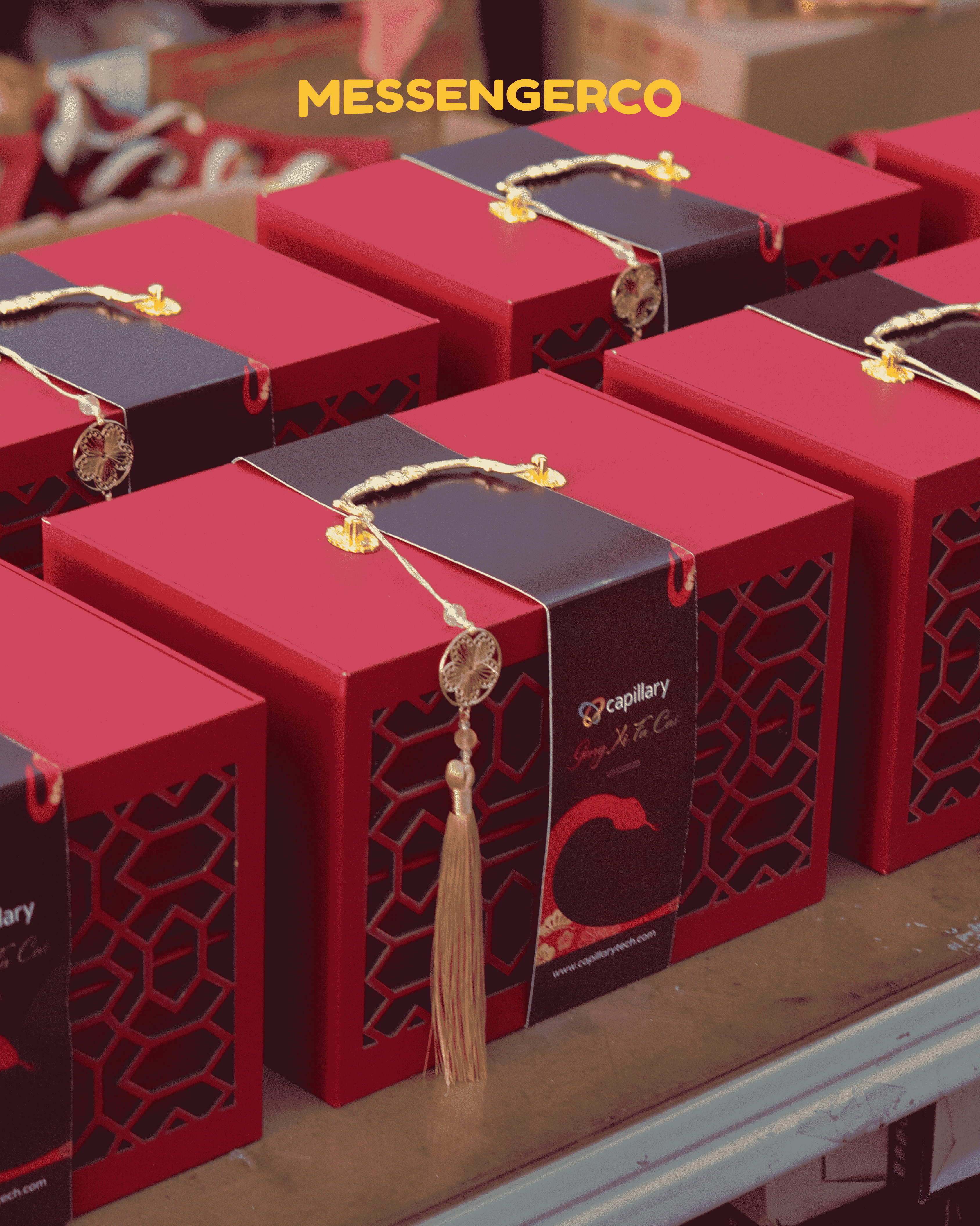 Rows of red Messengerco Imperial CNY gift boxes with Capillary logo and golden tassel handles lined up for corporate gifting.