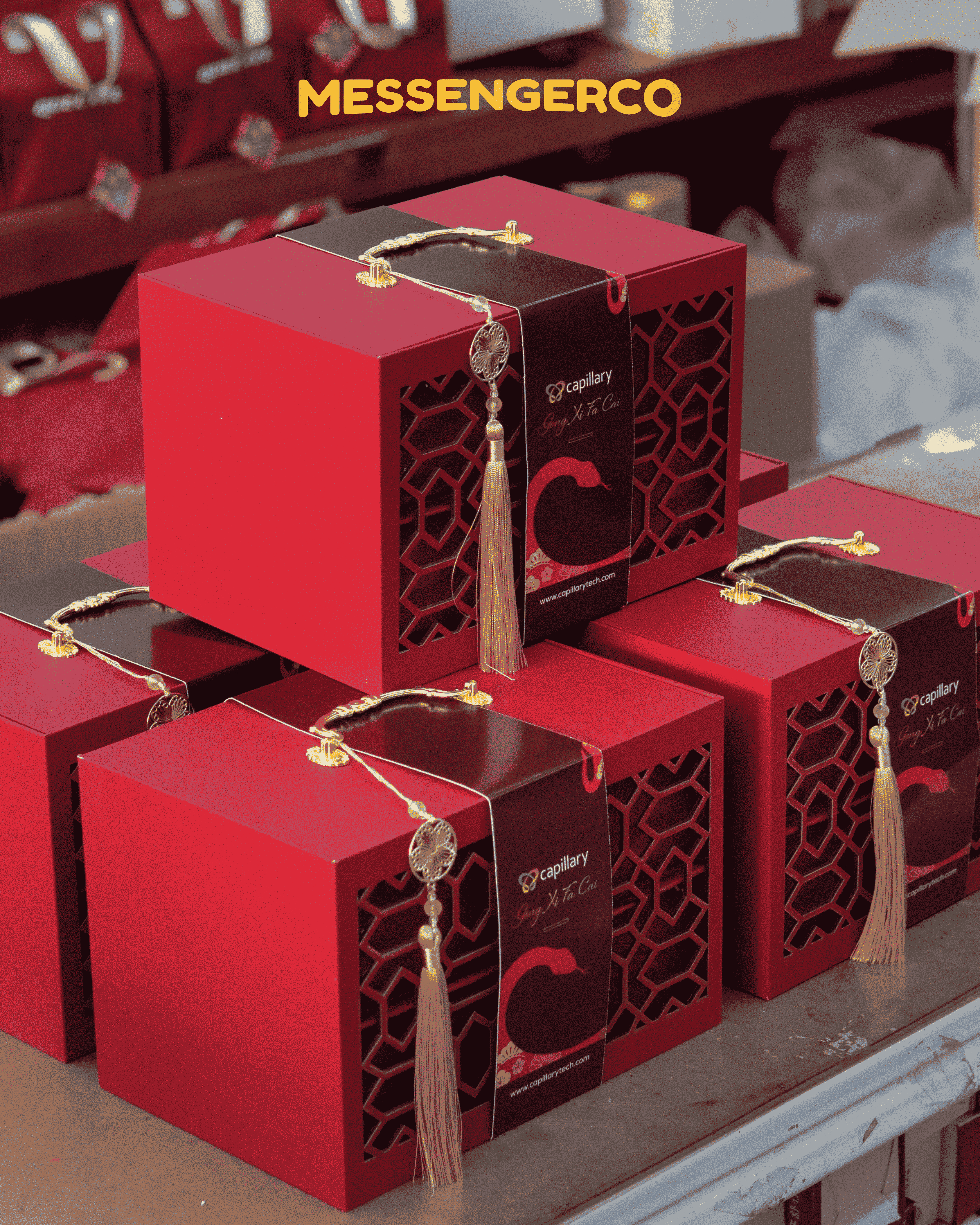 Stack of red Messengerco Imperial CNY gift boxes with Capillary logo and golden tassel handles stacked for gifting.
