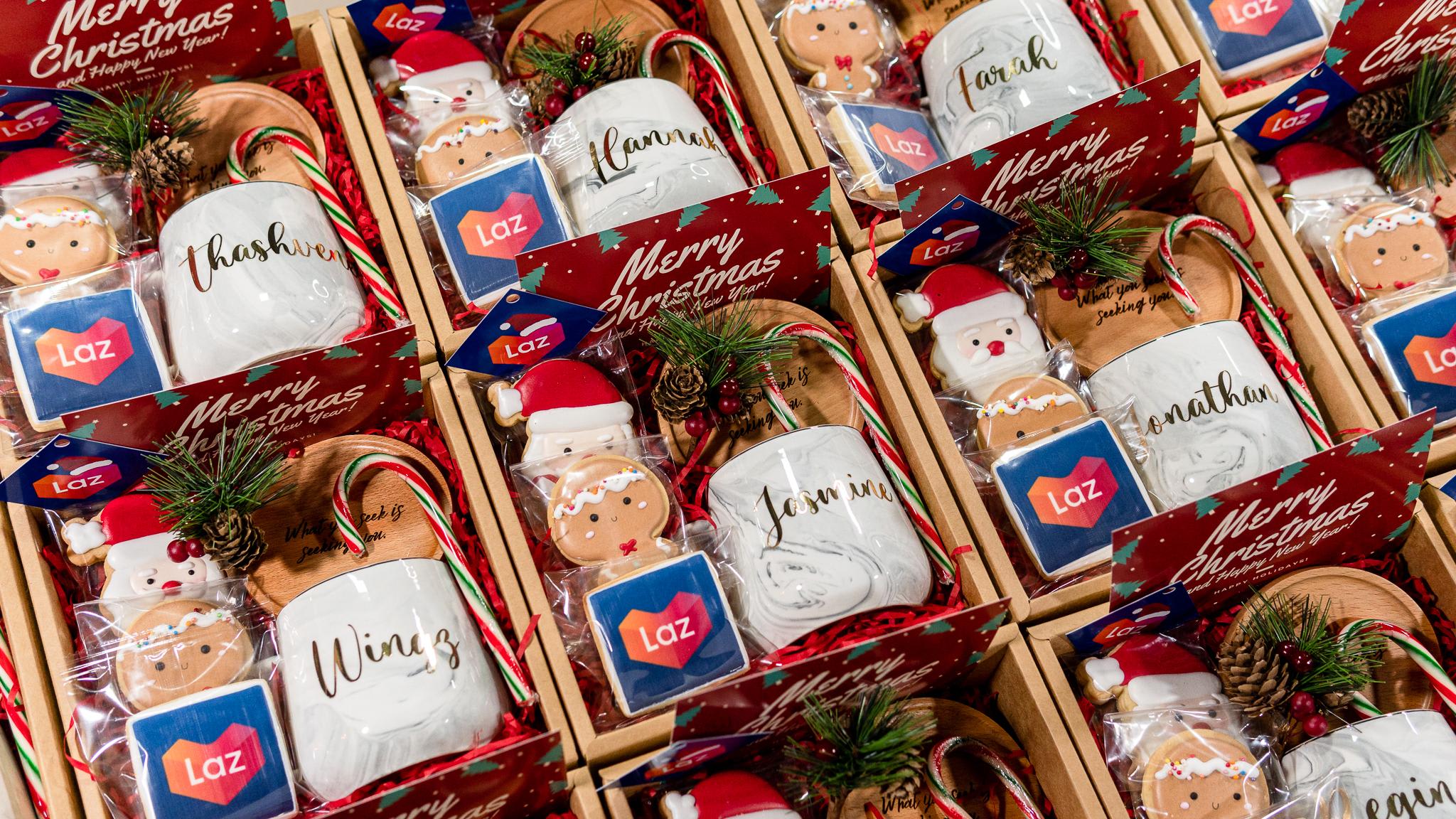 Christmas gifts for corporate client, Lazada containing lines of gift sets containing glass mug with personalised name, gingerbread cookies with santa face, cookies with Lazada company log, coaster in gift box.