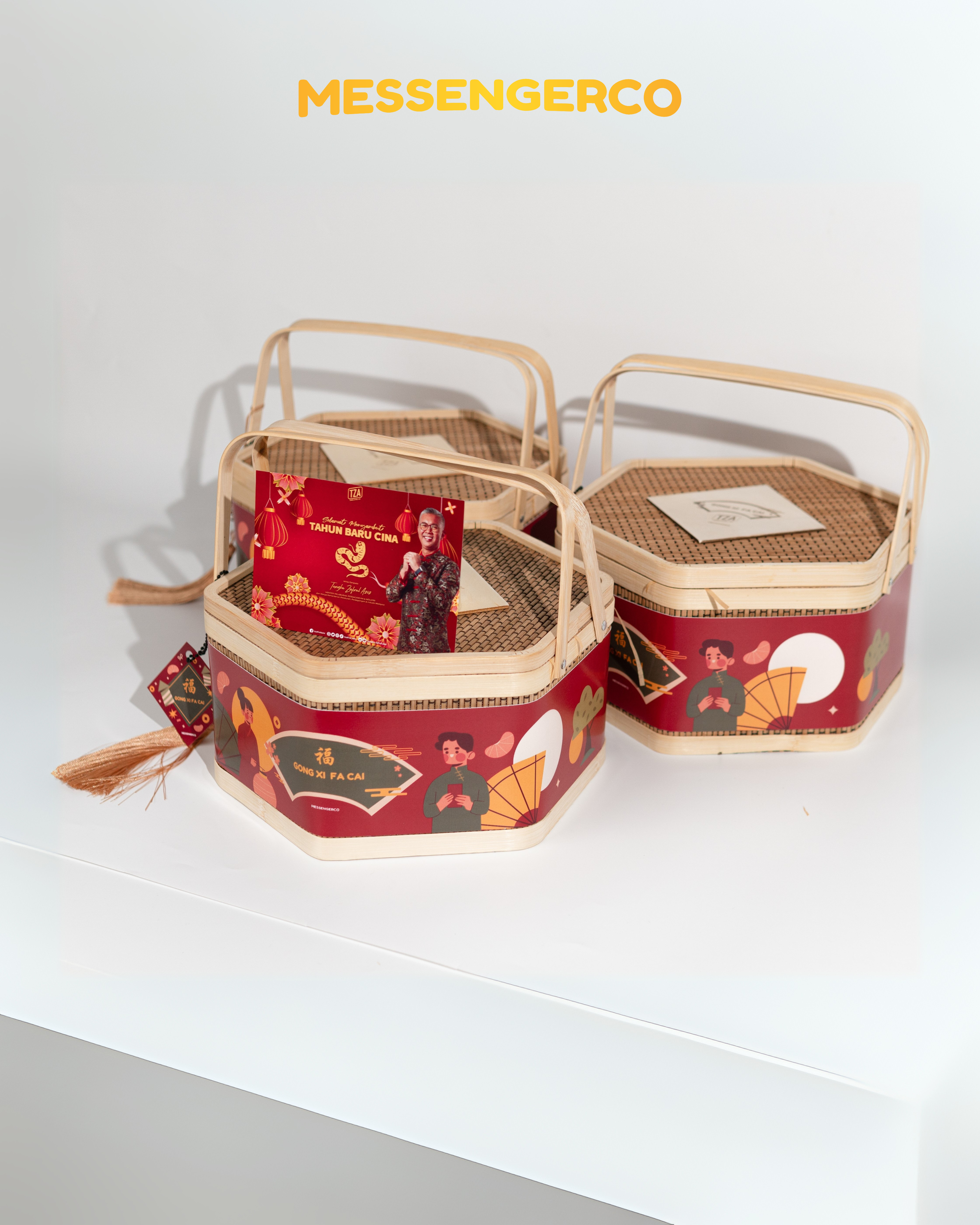 Three hexagonal bamboo gift baskets with woven lids and red CNY cards positioned on top for festive presentation.