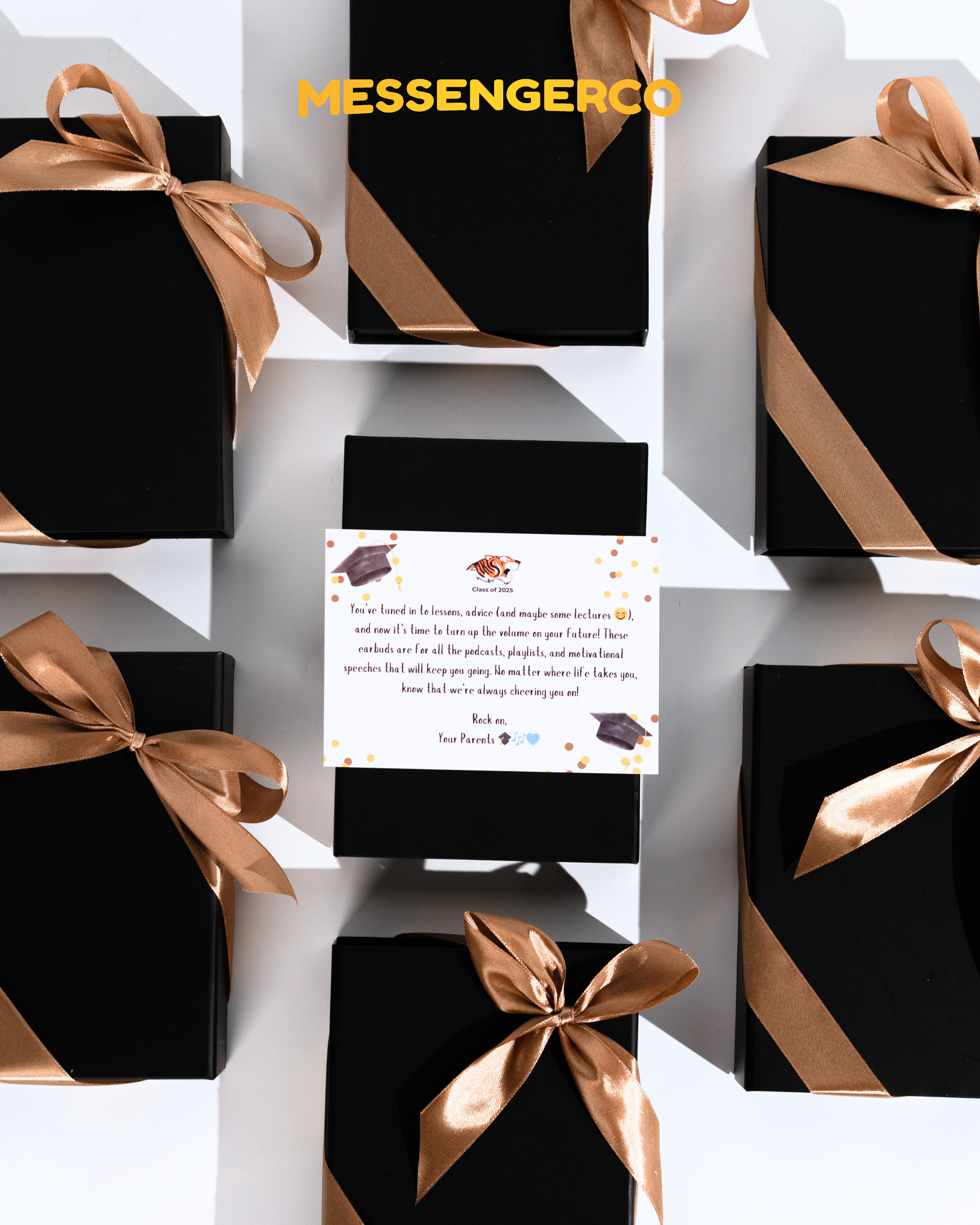 set of black gift boxes with gold satin ribbons, one open to reveal graduation appreciation card and earbuds gift