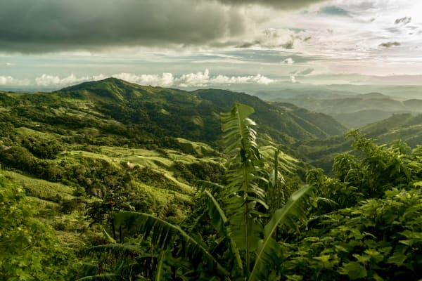 Mist-shrouded mountains rise above rolling green forested hills in Costa Rica