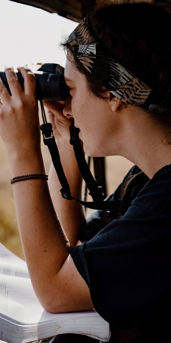 Students with binoculars observing wildlife on the savanna