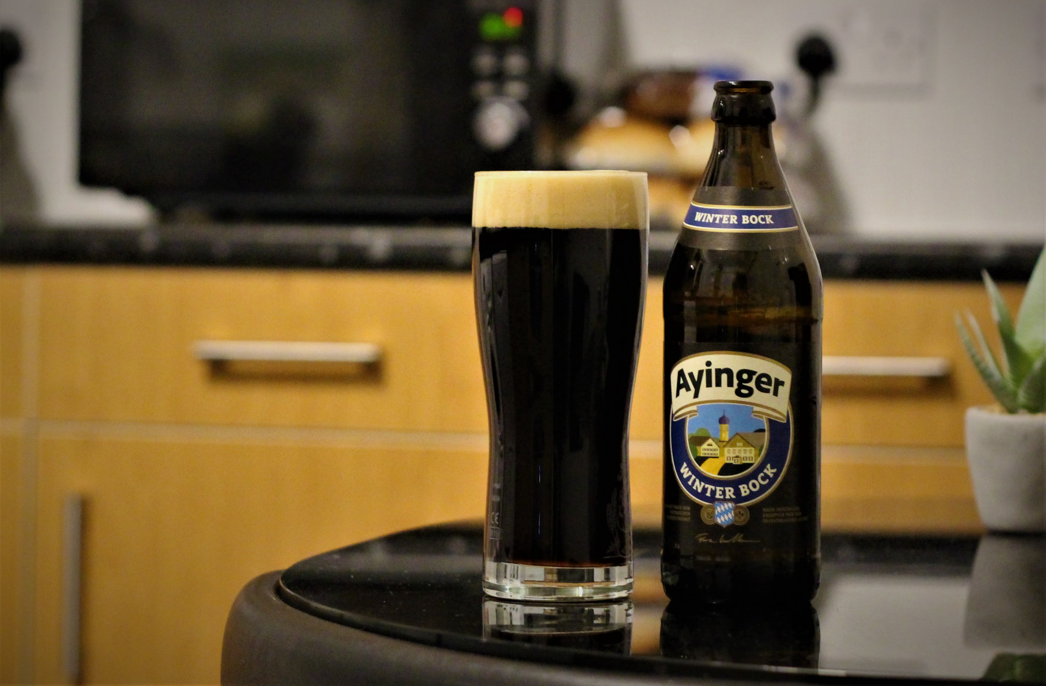 photo of ayinger beer in a glass next to the bottle