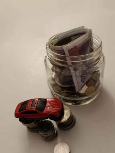 Car Savings Concept: Small Car, Coins and Banknotes Jar