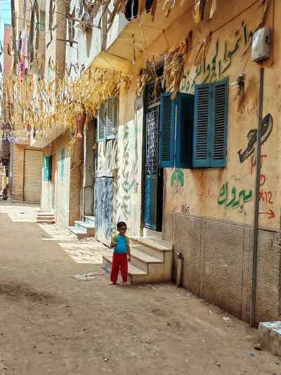 Little Boy in a Village Alley with Traditional Hajj Decorations