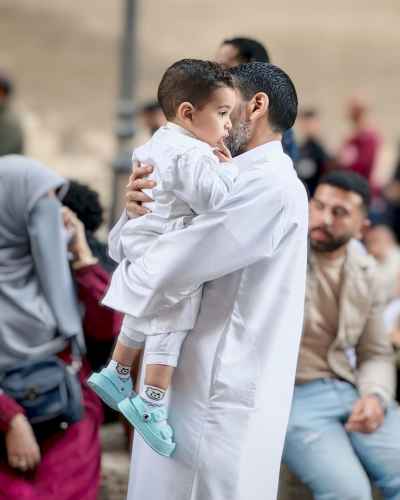 Father Carrying His Son in White Jalabeyas for Eid Prayer