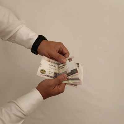 Egyptian Pound Banknotes Handed Between Two People