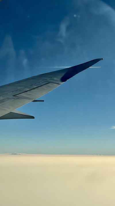 Airplane Wing View Above Clouds from Passenger Window