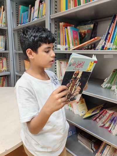 Child Reading Illustrated Book at Library Shelf
