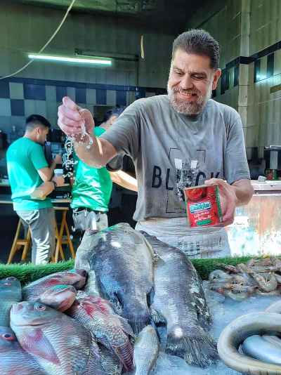 Egyptian Fish Vendor Spraying Water on Fresh Catch, Sayeda Zeinab Market