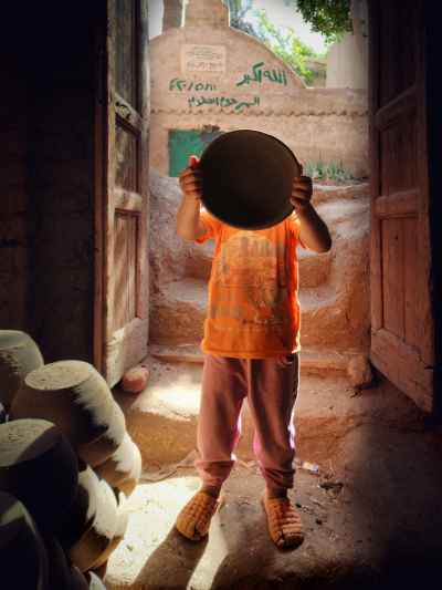 Child Holding Clay Plate at Pottery Workshop Entrance, Monufia
