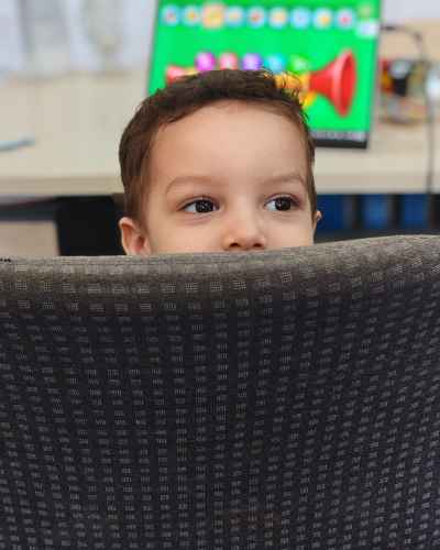 Child Peeking Behind Chair in Classroom Activity